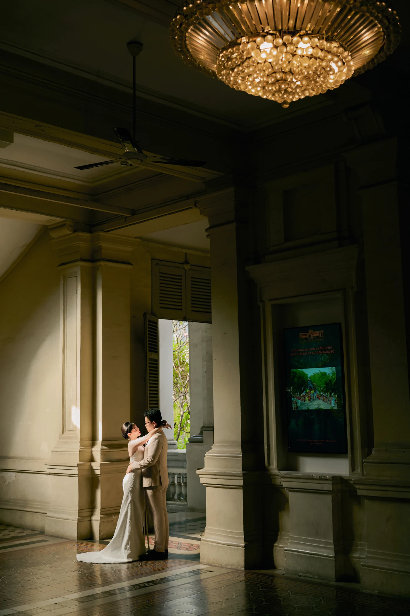 Small beneath a chandelier, an embrace in the doorway light of the great hall