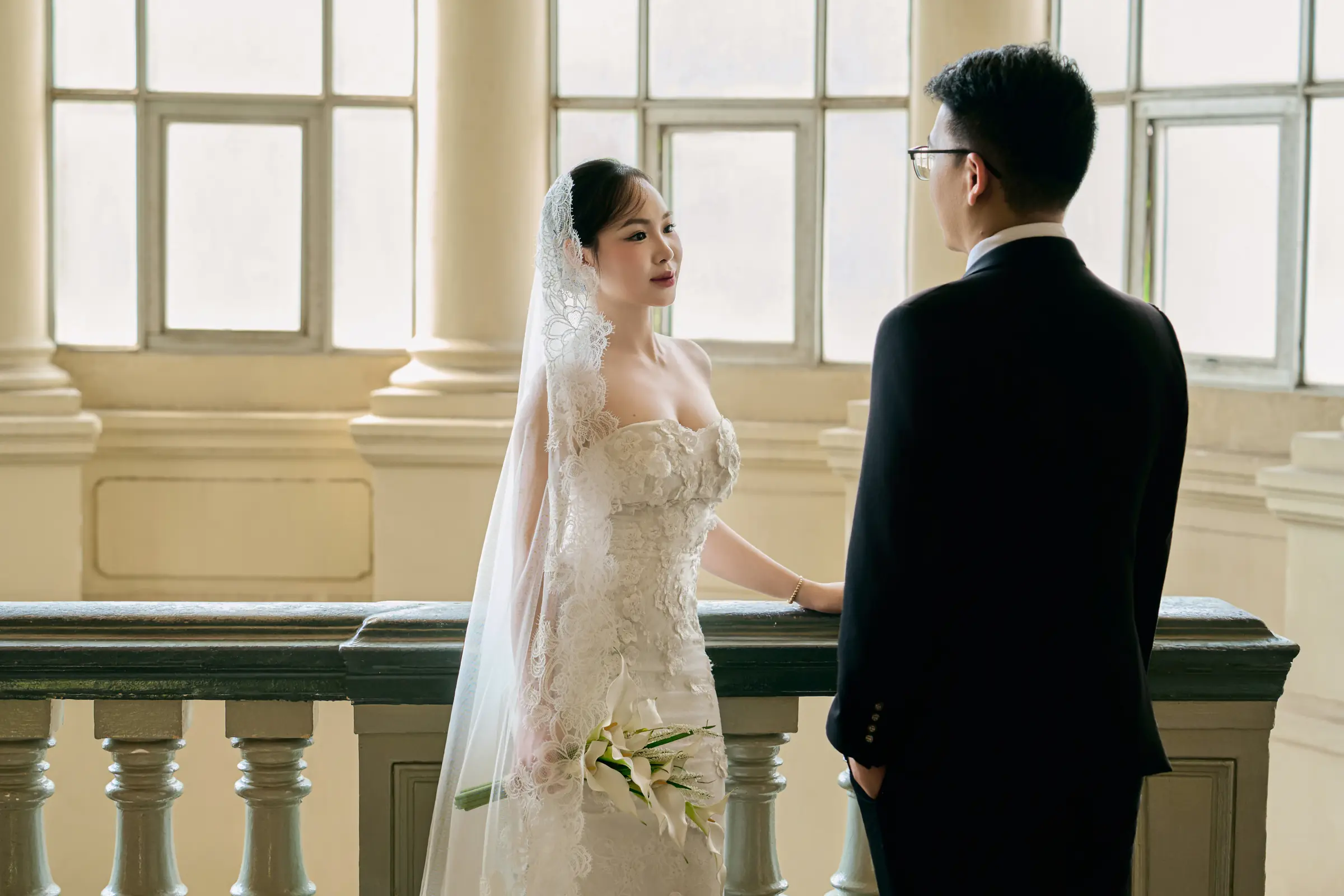 The bride in her veil, facing the groom